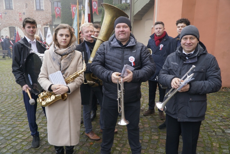 koiety i mężczyźni trzymający w dłoniach instrumenty dęte. uśmiechają się do zdjęcia.